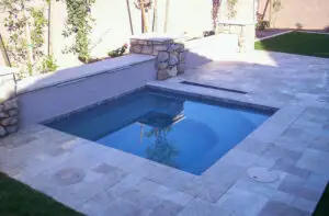 Elegant backyard spa with stone accents and travertine tile, creating a luxurious and peaceful outdoor oasis.