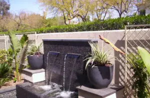 Elegant backyard water feature with dual waterfalls and potted plants, adding a touch of tranquility to the outdoor space.