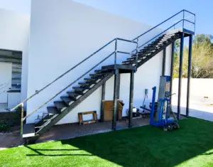 Modern outdoor metal staircase with railing, attached to a white building, designed for functional outdoor access.