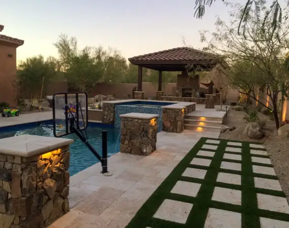 Luxurious backyard featuring a pool with stone pillars, basketball hoop, and an outdoor gazebo with a fireplace.