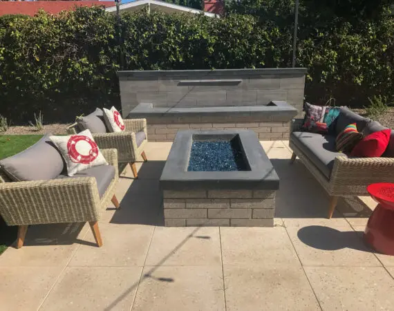 Modern outdoor fire pit with glass stones, surrounded by comfortable wicker seating and vibrant cushions, set on a stylish patio.