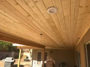 Patio construction in progress featuring a newly installed wooden ceiling with recessed lighting.