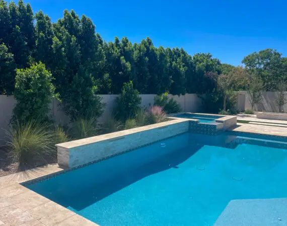 Pristine backyard pool with a stone deck, elegant raised spa, and lush landscaping providing a private and relaxing atmosphere.