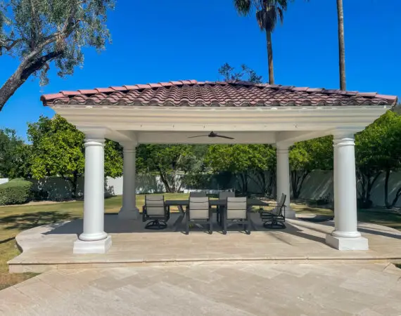 Elegant outdoor pavilion with tiled roof and classic columns, providing shaded dining area with modern patio furniture.