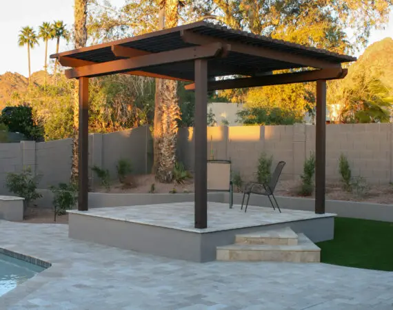 Elevated patio with a wooden pergola and outdoor seating, surrounded by desert landscaping and mountain views.