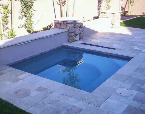 Elegant backyard spa with stone accents and travertine tile, creating a luxurious and peaceful outdoor oasis.