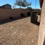 Side yard with gravel and an air conditioning unit, bordered by a block wall, showing a blank space ready for landscaping and design improvements.